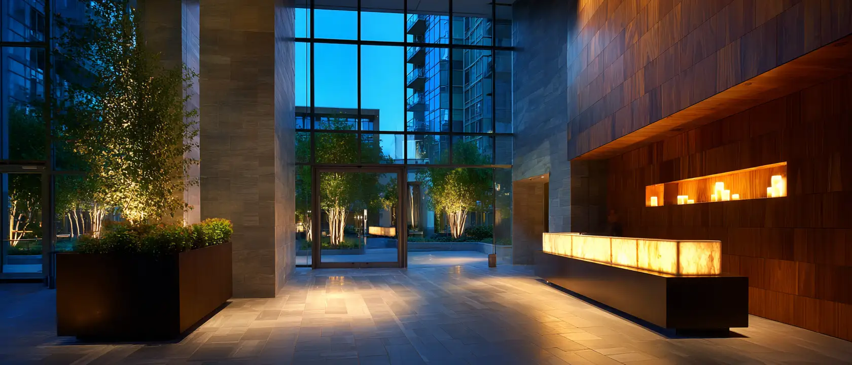The lit lobby and reception desk of a modern condominium building in the evening