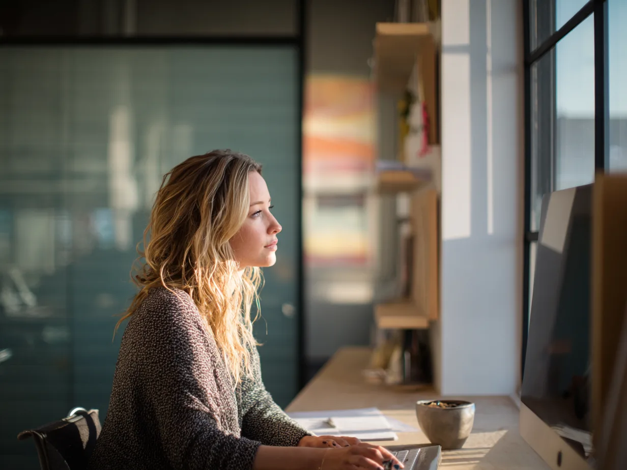 A property manager at work at her desk in a bright modern office, looking out over her monitor